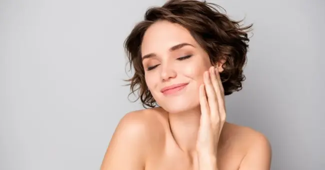 Smiling woman touching smooth skin, enjoying Facial Treatments in Greenville, SC Smiling woman touching smooth skin, enjoying Facial Treatments in Greenville, SC