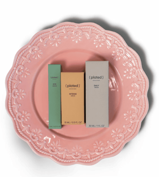 Three boxed skincare products on pink plate